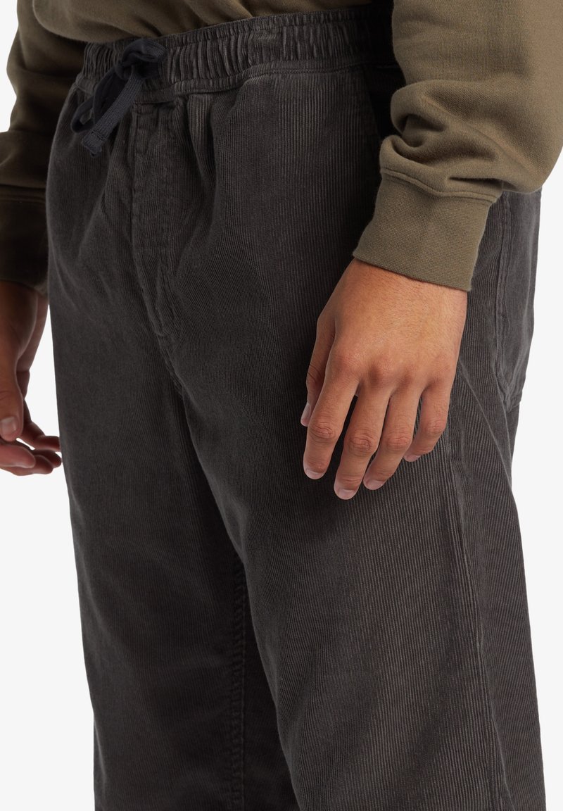 Donkergrijze corduroy broek met een ribbelstructuur, elastische tailleband en trekkoord. Voorzien van zijzakken en een relaxte pasvorm.