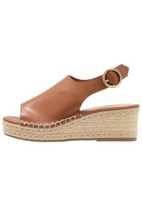 Sandale compensée en cuir brun avec orteils ouverts et bride de cheville, dotée d'une boucle en métal ronde et d'une plateforme en jute tressé. Texture lisse, design élégant.