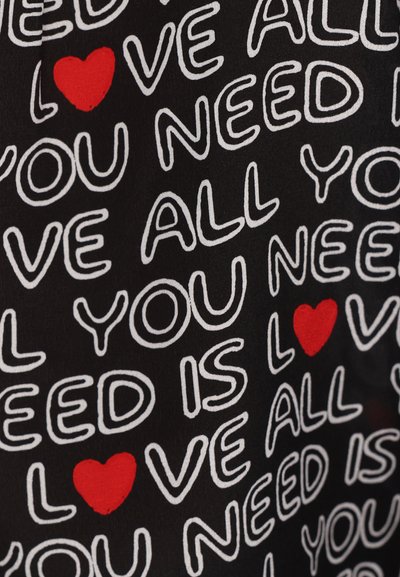 Black fabric featuring white text that reads "ALL YOU NEED IS LOVE" with a red heart accent. Playful lettering style, repeated pattern.