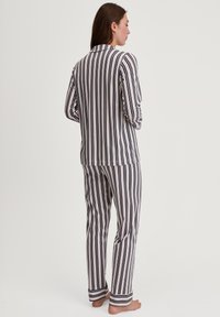 Gestreepte pyjama set in marineblauw, crème en roze. Langsleeve top en bijpassende broek met omgeslagen zoom en een relaxte pasvorm. Zachte stoftextuur.