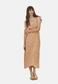 Vestido maxi de tela melocotón con un patr�ón de paisley; diseño sin mangas, ligera forma en A, complementado con un collar de cuentas y sandalias doradas.