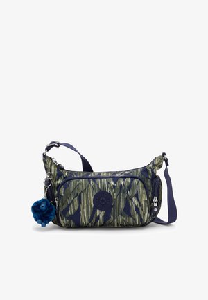 Petit sac à épaule avec motif abstrait vert et marine, poche avant zippée, bandoulière marine réglable et porte-clés en peluche bleu.