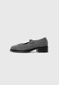Gray knit Mary Jane shoe with low block heel and black sole, featuring a single looped strap on a plain white background.