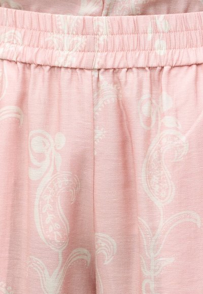 Ροζ ύφασμα με λευκό φλοράλ μοτίβο paisley και ελαστική ζώνη μέσης, που δείχνει υφή και ραφές.