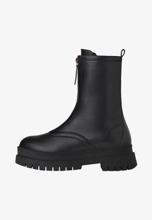 Bottine en cuir noir avec fermeture éclair latérale, semelle en caoutchouc épaisse, texture lisse et design minimaliste. Comprend une languette pour un enfilage facile.