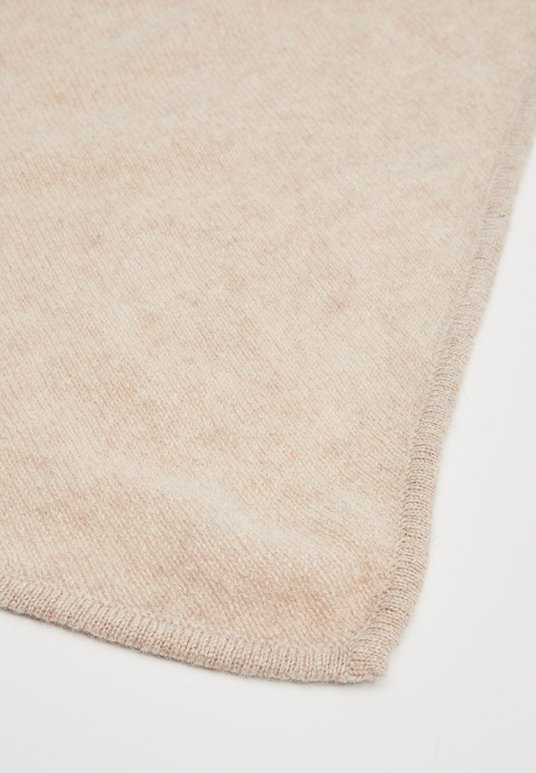 Hellbeige gestrickte Decke, die über eine weiche Textur, ein dezentes Muster und sauber bearbeitete Kanten verfügt. Sie hat eine rechteckige Form.