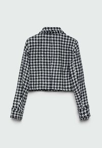 Veste courte noire et blanche à manches longues avec un motif pied-de-poule, vue de dos sur un fond uni.