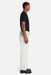 T-shirt nera a maniche corte, abbinata a jeans bianchi a vita alta con orlo sfilacciato e scarpe nere con suola spessa.