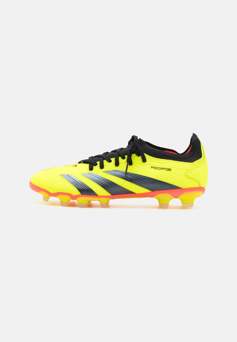 Botín de fútbol amarillos brillantes con rayas negras, parte superior sintética texturizada, cordones negros y suela con acentos naranjas y múltiples tacos.