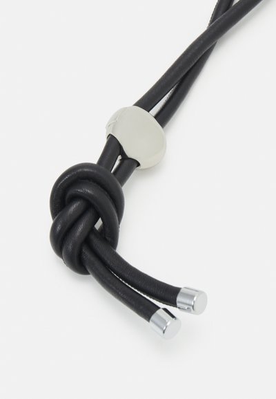 Black leather cord with a knotted center, featuring a silver metal accent and rounded ends. Smooth texture, minimalist design.