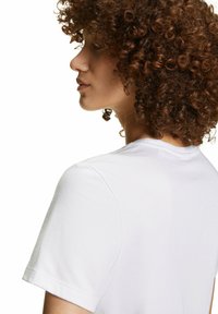 T-shirt bianco in cotone con maniche corte, dotato di un classico collo tondo e una superficie liscia. Nessun motivo o accentuazione visibile.