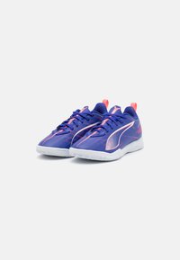 Zapatillas deportivas azules con acentos en rosa, parte superior texturizada y suelas de goma blanca. Las características incluyen un cuello acolchado y cordones en contraste.