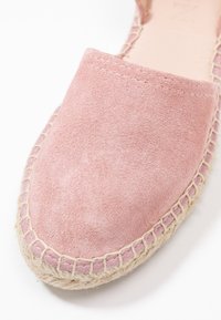 Różowy zamszowy espadryl z okrągłym czubkiem i jutową podeszwą, z przeszytym brzegiem i gładką teksturą.