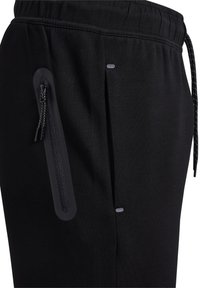 Czarne spodnie sportowe z bliska, pokazujące elastyczny pas, pionową kieszeń na zamek błyskawiczny z podwójnymi suwakami oraz odblaskowy detal przy szwie bocznym.