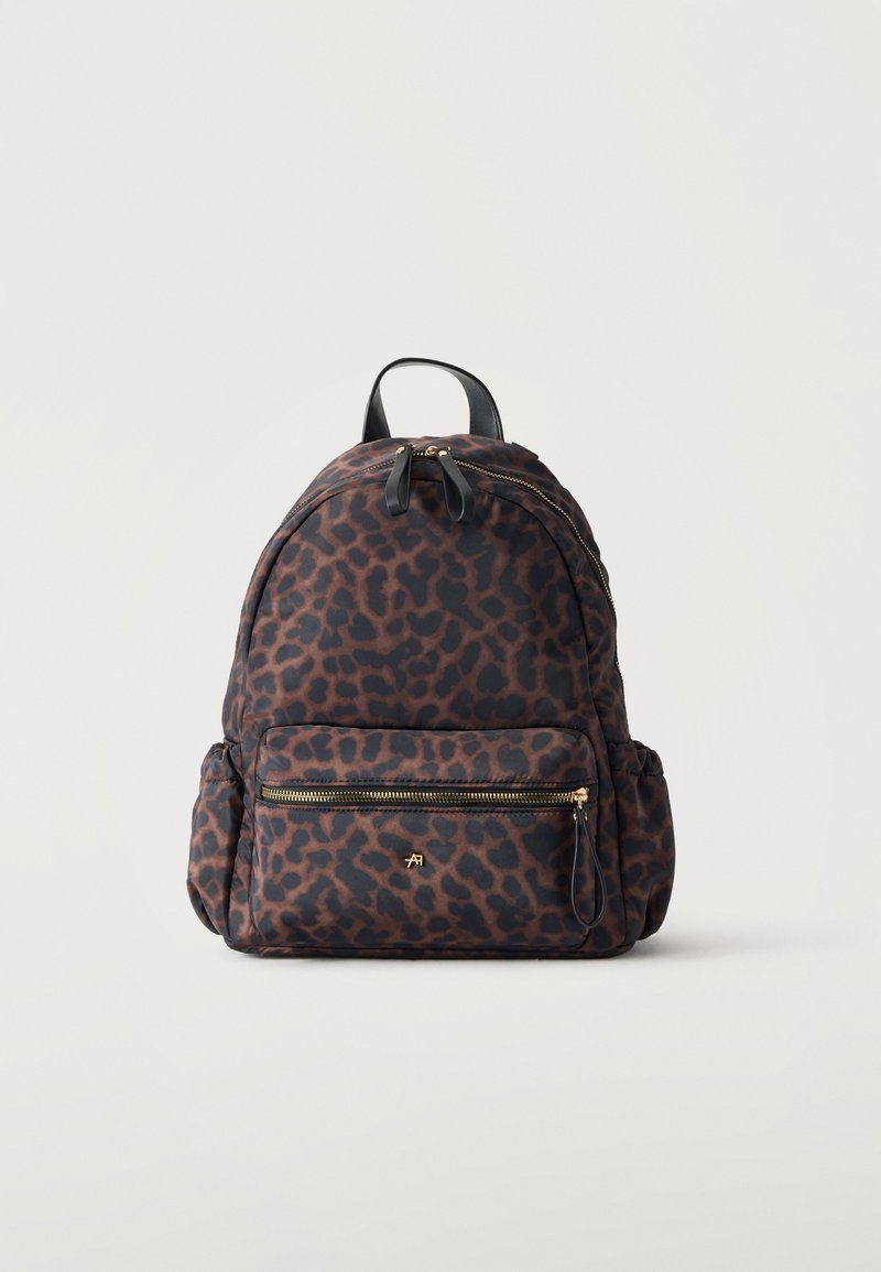 Sac à dos avec imprimé léopard marron et noir, avec une poche zippée devant, des poches latérales et une poignée noire sur le dessus.