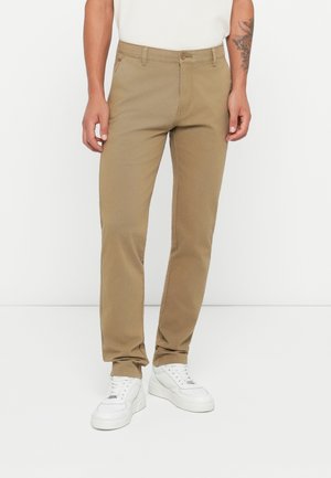 Beige cotton chinos with a straight-leg cut, featuring a button closure and side pockets, paired with white sneakers.