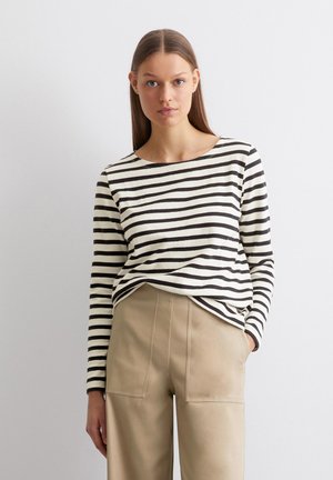 Zwart-wit gestreepte langemouwen top met een bootcoupe, gecombineerd met beige wijde broek met zakken aan de voorkant en een structuurstof.