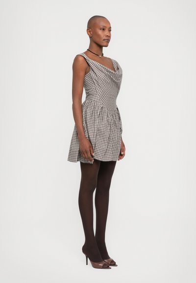 Zwart-wit geblokt jurk met een cowl neckline en een getailleerde bovenkant. Heeft een uitlopende rok en dunne banden, gecombineerd met zwarte panty’s en schoenen.
