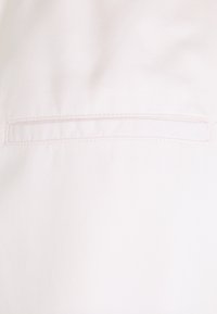 Vitt tyg med en fin diagonalt väv, med en enda horisontell söm i mitten. Slät yta, minimal detaljering.