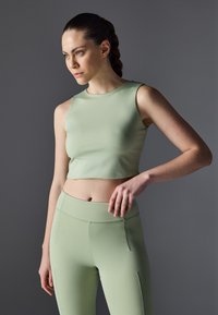 Top corto ajustado de color verde menta con un escote redondo, combinado con leggings de tiro alto a juego. Ambos artículos tienen una textura suave y costuras mínimas.