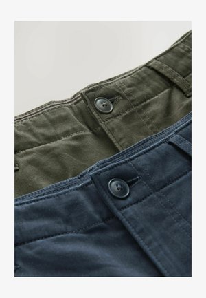 Izstādītas divas bikses. Vienas ir olīvzaļas, otras - tumši zilas, abām ir pogu aizdare un struktūrveida kokvilnas audums.