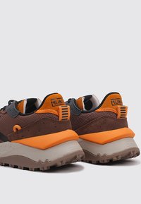 Baskets de plein air marron avec une tige texturée, des accents orange et une semelle rembourrée dotée d'un motif de traction robuste pour une meilleure adhérence.