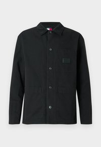 Μαύρο μπουφάν από βαμβάκι, με γιακά από κοτλέ, μπροστινές τσέπες και κούμπωμα με κουμπιά. Διαθέτει τετράγωνη ετικέτα στην τσέπη του στήθους.