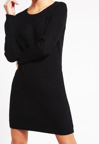 Abito nero in maglia con maniche lunghe, caratterizzato da un motivo a zigzag, scollatura rotonda e una vestibilità morbida, che arriva a metà coscia.