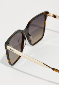 Square sunglasses with a tortoiseshell pattern, gradient lenses, and gold metal accents on the arms. Features a logo engraved on the temple.