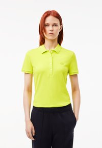 Limonkowa koszulka polo z kołnierzykiem, krótkimi rękawami i trzema guzikami, z delikatnym logo na lewej piersi.