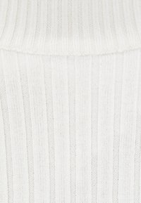 Tissu blanc côtelé présentant des rayures verticales avec une texture douce et un motif de tricot régulier. Aucun détail décoratif supplémentaire.