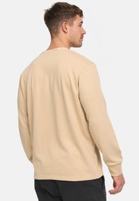 Beige langærmet sweatshirt lavet af blødt materiale med en afslappet pasform, der har rund halsudskæring og et minimalistisk design, uden mønstre eller accenter.