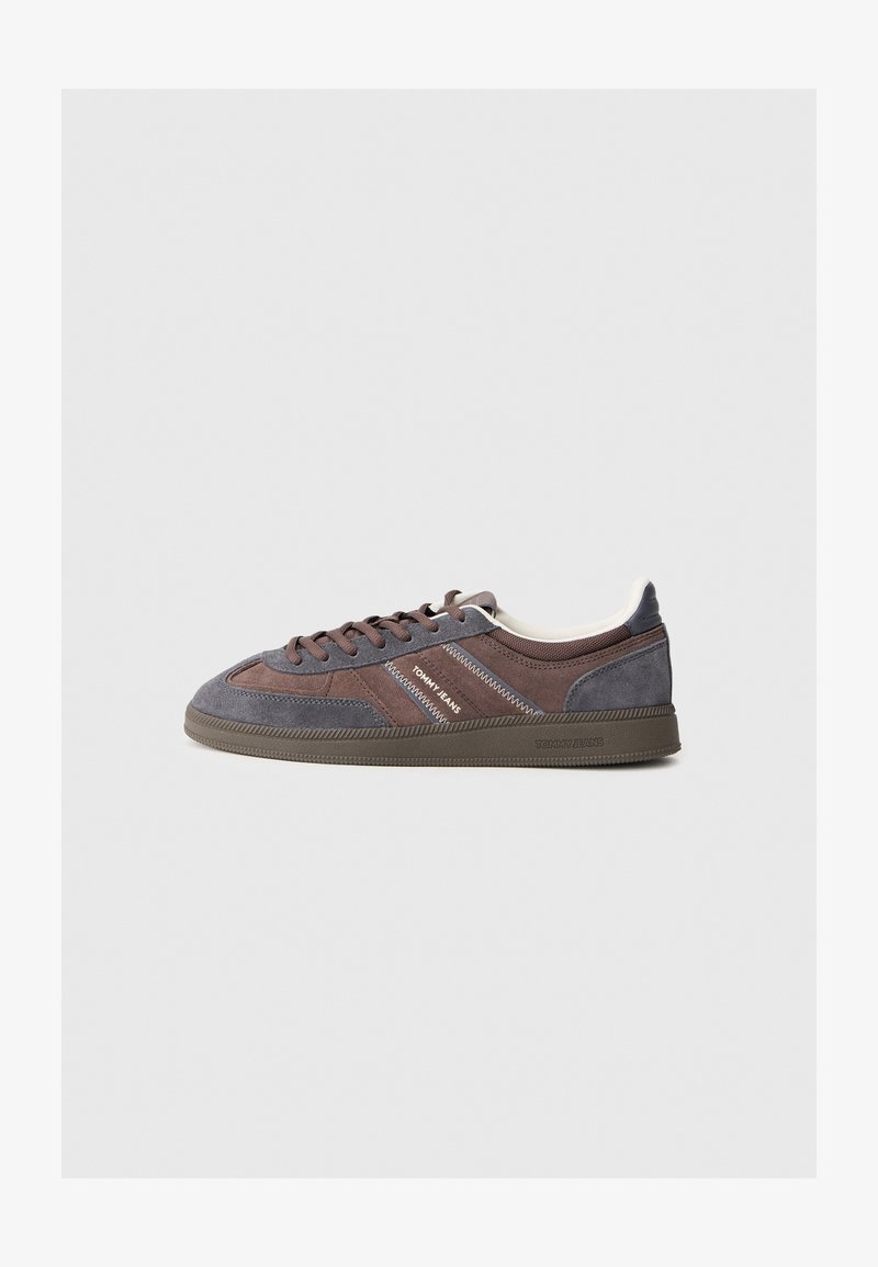 Semišové tenisky v odtieňoch hnedej a šedej, s guľatými šnúrkami, textúrovanou podrážkou a bielymi akcentmi na jazyku a logu.