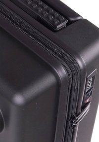 Black hard-shell suitcase with textured surface, dual zippers, and built-in combination lock. Features a top handle with grip texture.