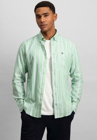 Camisa de rayas verdes y blancas con cuello abotonado, fabricada en un tejido ligero y con un pequeño logo en el bolsillo del pecho izquierdo.