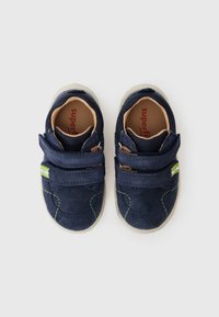 Navy blue suede children's shoes with two Velcro straps, contrasting green stitching, and a light gray sole. Interior features a tan insole.