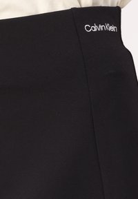 Svart Calvin Klein skjørt med en jevn tekstur og tettsittende design. Har et brodert logo på midjebåndet.