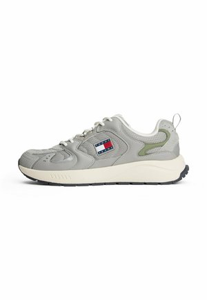 Graue sportive Sneaker aus Mesh- und Lederstoffen, mit runder Zehenpartie, weißer Sohle, grünen Akzenten und einem Logopatch an der Seite.