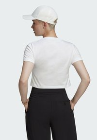 Balta trumpa marškinėliai su trumpomis rankovėmis, derinami su juodomis aukštai užkeltais kelnėmis, turinčiomis šoninę kišenę. Sportinė balta kepuraitė nešiojama atvirkščiai.