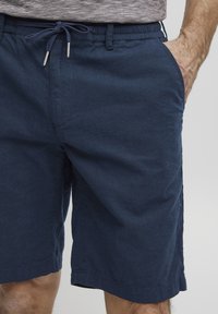 Marineblå shorts laget av mykt stoff, med elastisk midje og snøring samt sidelommer. Uformell og komfortabel design.