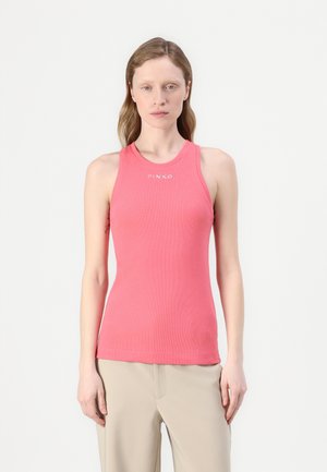 Pink ribbed tank top with a rounded neckline and logo detail at the chest, paired with light beige trousers. The fabric appears smooth and fitted.