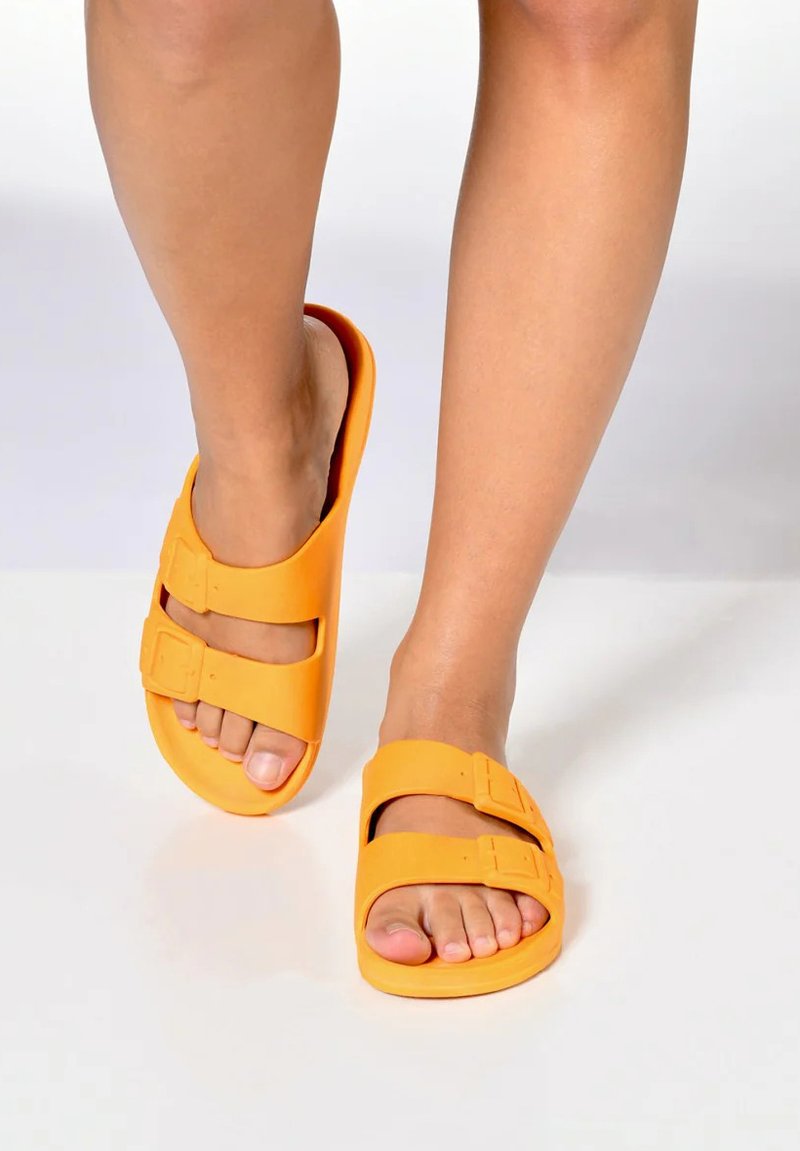 Sandales en caoutchouc orange avec deux boucles réglables, design ouvert à l'avant, texture lisse et forme courbée pour un ajustement confortable.