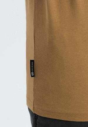 Bruine katoenen t-shirt met een slim fit, voorzien van een zwart "ombre" label aan de linkerkant van de zijnaad. Gladde textuur, korte mouwen, eenvoudig ontwerp.