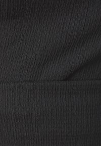 Texturert svart stoff med ribbet mønster, som viser en subtil glans og myk utseende. Egnet for ulike klesapplikasjoner.
