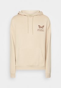 Sudadera con capucha beige hecha de tela suave, con bolsillo delantero, capucha con cordón y diseño estampado de mariposa con texto en el pecho.
