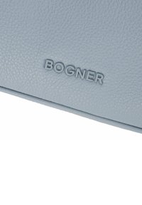 Portafoglio in pelle azzurro chiaro con superficie testurizzata e logo "BOGNER" impresso. Forma rettangolare compatta con bordi puliti.