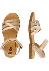 Alaston sandaalit, joissa on kimaltavat kultanauhat, litteä pohja ja säädettävä nilkkaremmi. Ominaisuuksiin kuuluu ristikkäinen muotoilu ja pehmeä tekstuuri. Brändi: Bull Boxer.