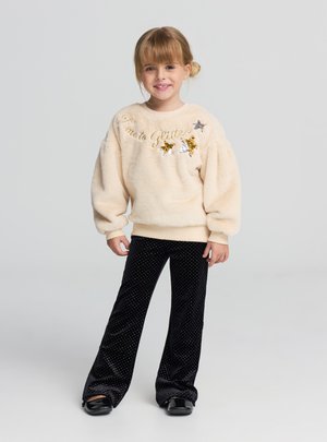 Maglione in pile color crema con ricamo "Time to Glitter" e paillettes decorative. Pantaloni in velluto nero con pois bianchi e design svasato.