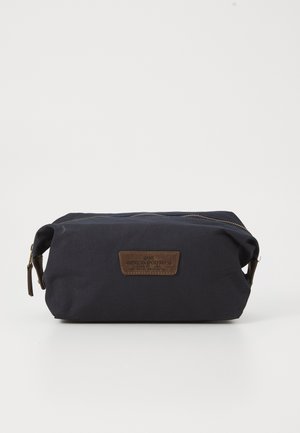 Small rectangular navy blue toiletry bag with brown leather brand patch and zipper, shown against plain white background.