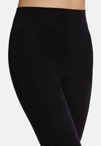 Leggings neri realizzati in materiale elasticizzato, con un alto waistband e una superficie liscia, progettati per comfort e flessibilità.